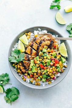 a bowl filled with chicken, corn and cilantro on top of white rice