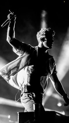 a man standing on top of a stage with his arms in the air while holding a microphone