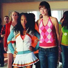 two young women standing next to each other in front of a group of people wearing colorful clothing