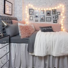 a bedroom with white brick walls and string lights on the headboard, along with gray bedding