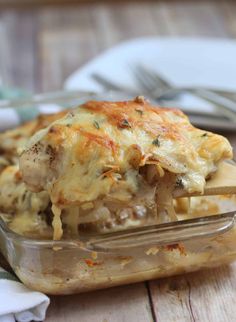 a casserole dish with meat and cheese on a wooden table next to a fork