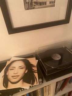 a record player sitting on top of a book shelf next to a framed photo and album