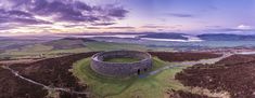 an aerial view of a round building on top of a hill in the middle of nowhere