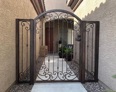 an iron gate in front of a house with a potted plant on the other side