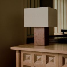 a lamp sitting on top of a wooden table next to a dresser in a room