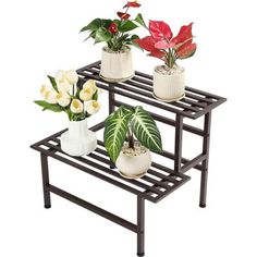 three potted plants are sitting on a black shelf with white and red flowers in them