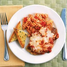 a white plate topped with pasta and sauce next to two slices of pizza on top of a wooden table