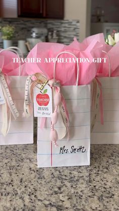 pink paper bags with ribbons tied to them on a countertop in front of a kitchen