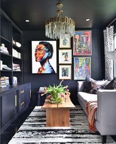 a living room with black walls and pictures on the wall, couches and coffee table