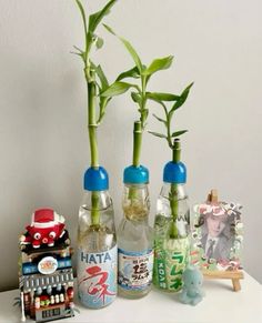 three bottles with plants in them sitting on a table next to toys and other items