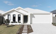 a white house with black shutters on the front and side doors, grass area in front