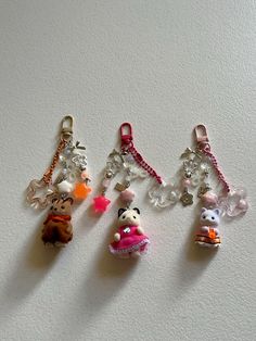 four keychains with various charms attached to them on a white surface in the shape of animals