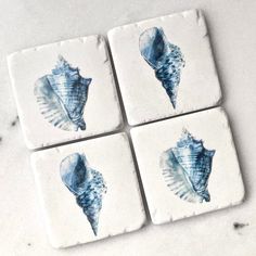 four coasters with sea shells painted on them