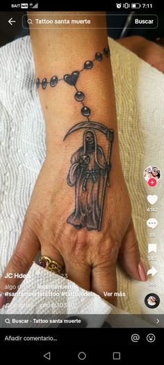 a woman's hand with a tattoo on the wrist and rosary hanging from it