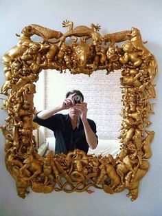 a man taking a selfie in front of a mirror with gold decorations on it