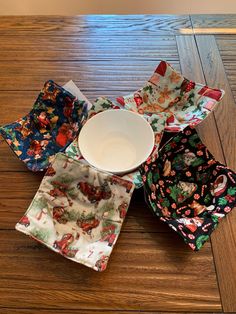 four different colored dishes sitting on top of a wooden table next to an empty bowl