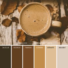 a cup of coffee sitting on top of a wooden table next to some brown leaves