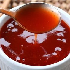 a spoon pouring ketchup into a white bowl