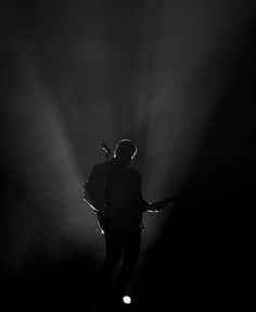 a man standing in the middle of a dark room with light coming from behind him