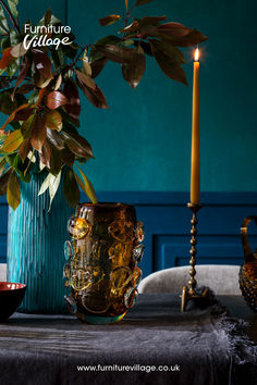 a table topped with vases filled with flowers next to a candle holder and bowl