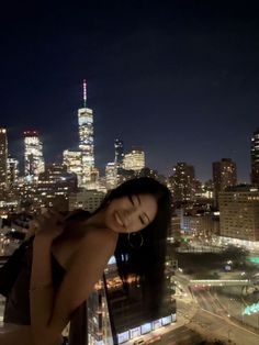 a woman standing on top of a tall building in front of a cityscape