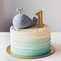 a birthday cake with a whale on top and the number 1 in gold glitters