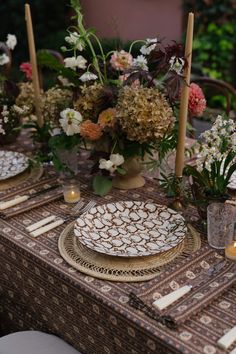 the table is set with plates, candles and flowers