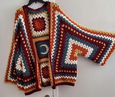 a crocheted sweater hanging on a hook next to a coat hanger with hooks