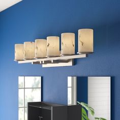 a bathroom with blue walls and a mirror on the wall next to it is a vanity light