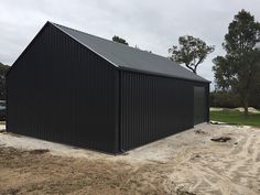 a black metal building sitting on top of a dirt field