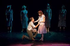 a man kneeling down next to a woman on top of a stage