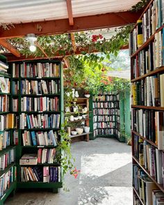 a room filled with lots of books under a pergolated roof covered in plants