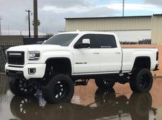 a white truck parked in front of a building on top of a wet parking lot