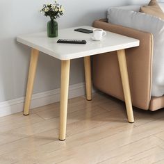 a small table with a remote control on it next to a couch and coffee cup