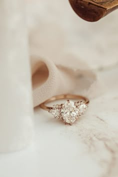 a three stone diamond ring sitting on top of a white cloth