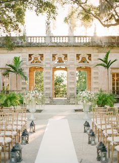 an outdoor ceremony setup with white flowers and candles in front of the entrance to a building