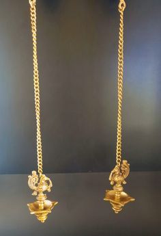 two gold necklaces are shown on a black surface and one is hanging from the side