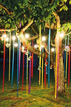 a tree with lights hanging from it's branches and some ribbons on the ground