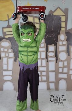 a young boy dressed as the incredible hulk with a skateboard on his head and arms