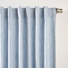 a blue curtain hanging on the side of a window with white walls and curtains behind it