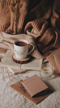 a cup of coffee sitting on top of an open book next to some glasses and books