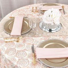 the table is set with pink napkins and silver plates