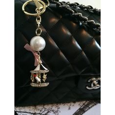 a black purse with a key chain attached to it and a pearl charm hanging from the front