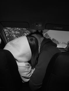 black and white photograph of a person sleeping in the back seat of a car with their head on someone's shoulder