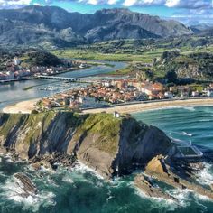 an aerial view of the coast and coastline in front of some mountains with houses on it