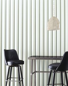 two black leather stools in front of a table with a lamp hanging from it