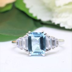 an aqua and white topazte ring with three baguets on the side