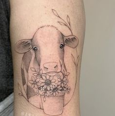 a black and white tattoo of a cow with flowers in it's mouth on the leg