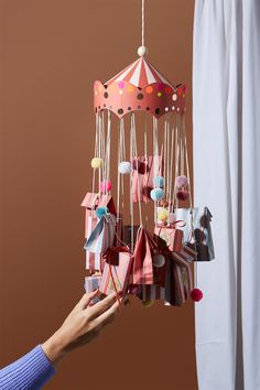 a person is holding an origami mobile in front of a curtain and window