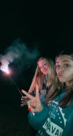 two girls are holding sparklers and pointing at the sky with their fingers in the air